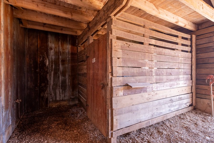 A stall doorway in the old stable with the number 58 painted on the wooden door, surrounded by aged boards and shavings underfoot.